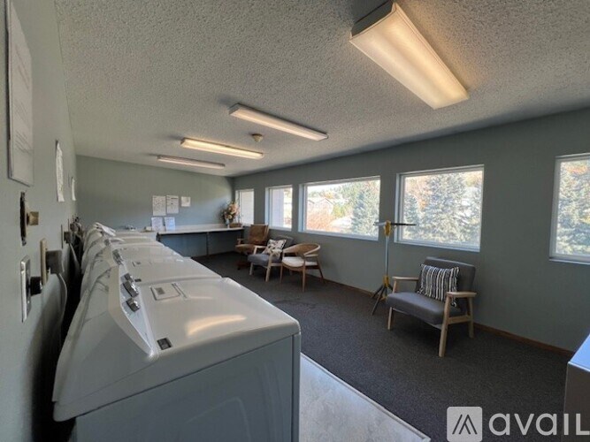 A laundry room with a washer and dryer, a chair, and a window.