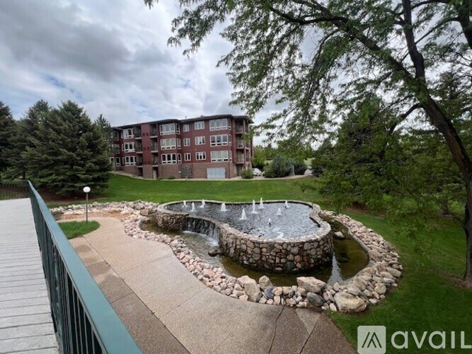 A fountain in the middle of a garden with a building in the background.