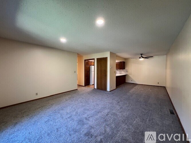 A spacious room with a carpeted floor and a ceiling fan.