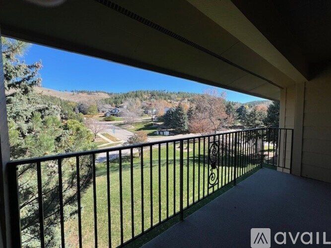 A balcony with a black railing overlooks a green landscape.