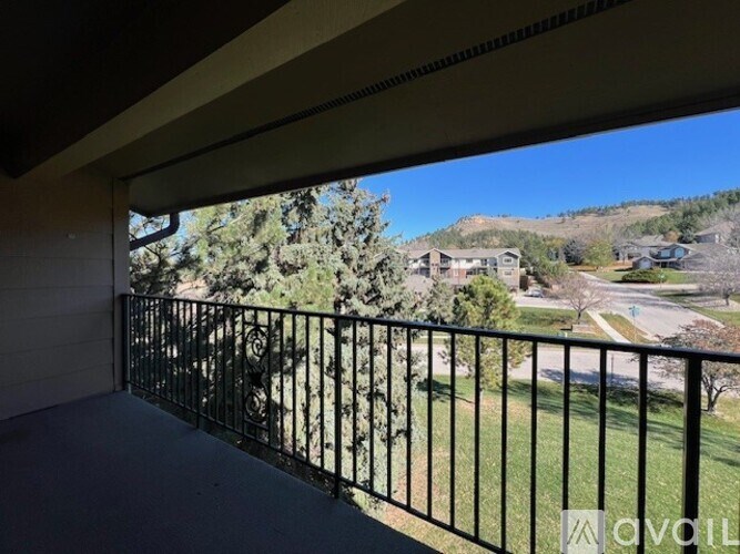 A balcony with a black railing overlooks a residential area.
