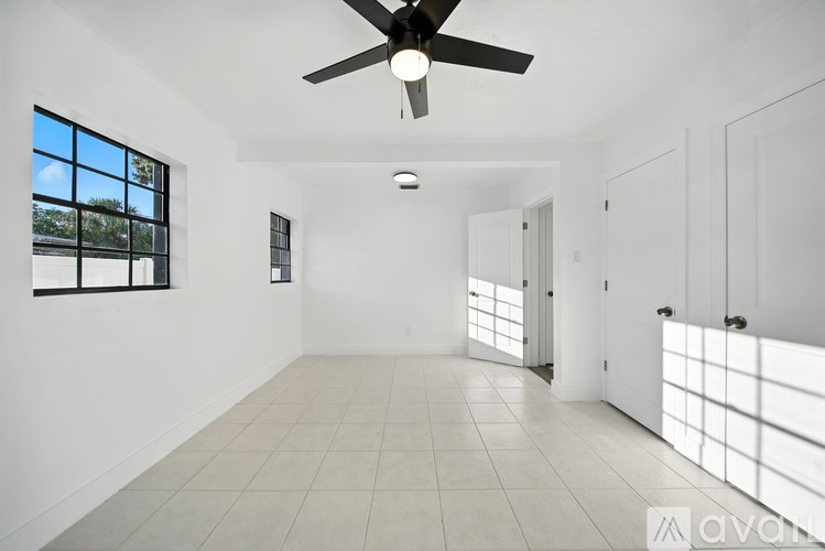 A spacious room with a ceiling fan and large windows.