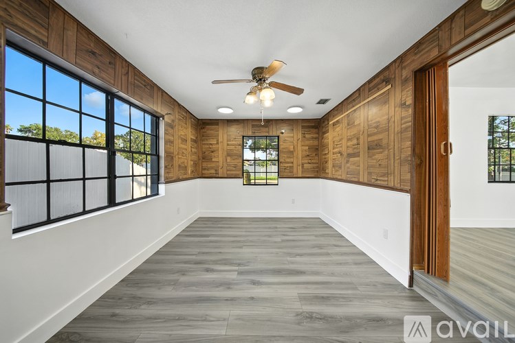 A spacious room with wooden walls and a ceiling fan.