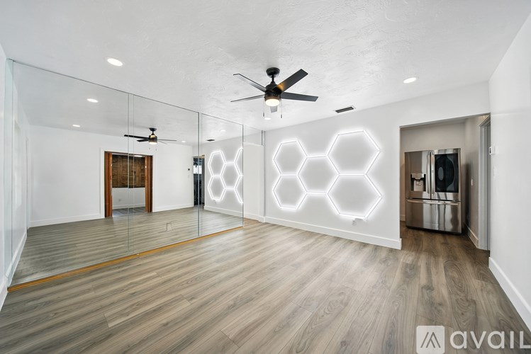 A spacious room with a ceiling fan and hexagonal light designs on the wall.
