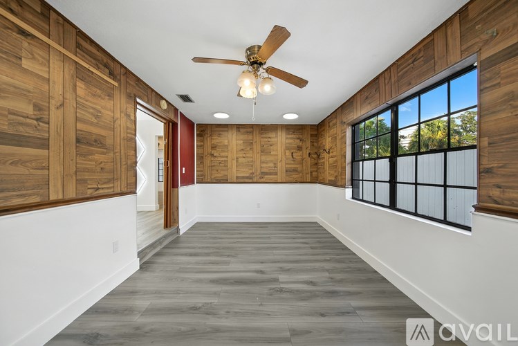 A spacious room with wooden walls and a ceiling fan.