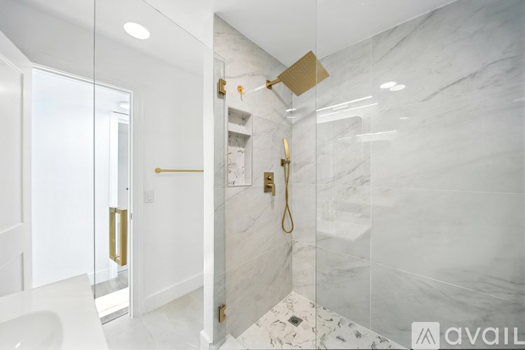 A bathroom with a marble wall and a gold shower head.