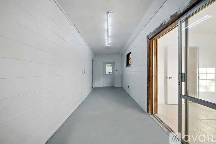 A long, narrow hallway with a door on the right and a window in the distance.