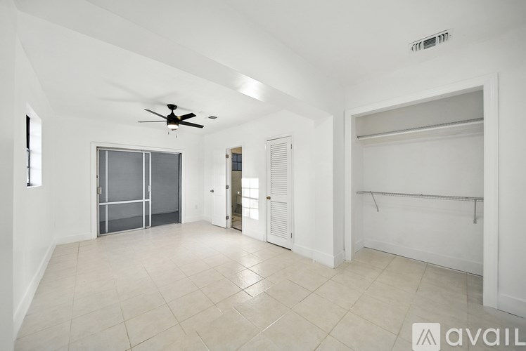 A spacious room with a ceiling fan and a large window.