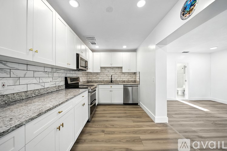 A kitchen with white cabinets and a marble countertop.