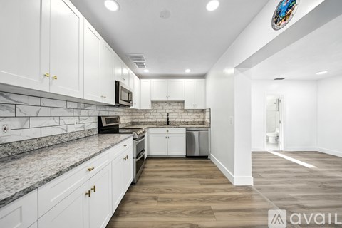 A kitchen with white cabinets and a marble countertop.