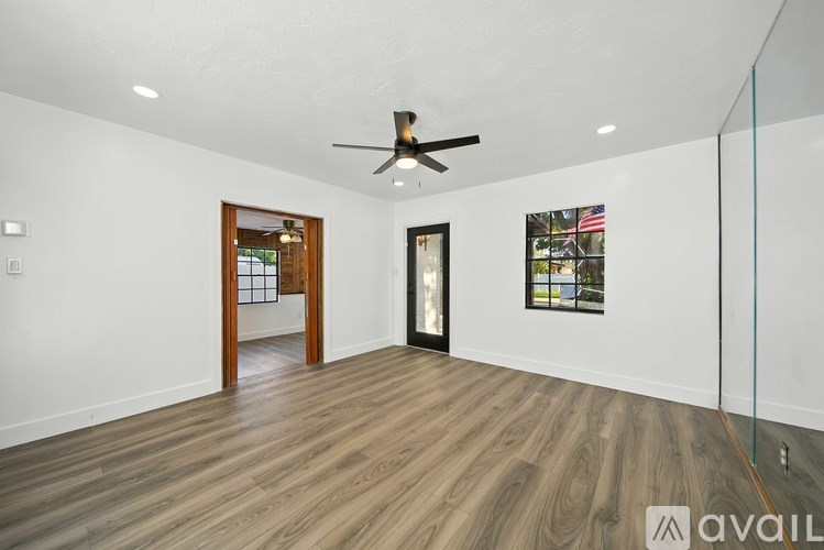 A spacious room with a ceiling fan and wooden flooring.