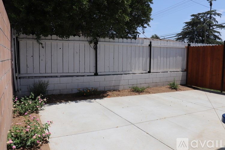 A backyard with a white fence and a brown gate.