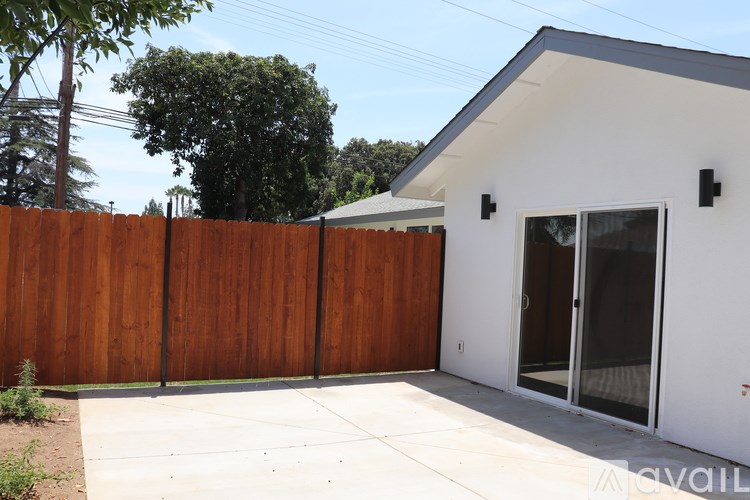 A white house with a brown fence and glass doors.
