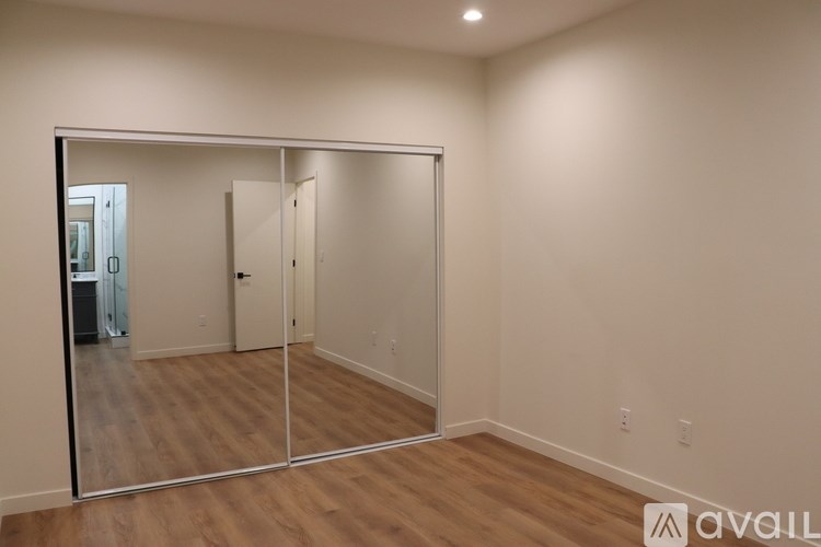 A room with a mirrored door and wooden flooring.