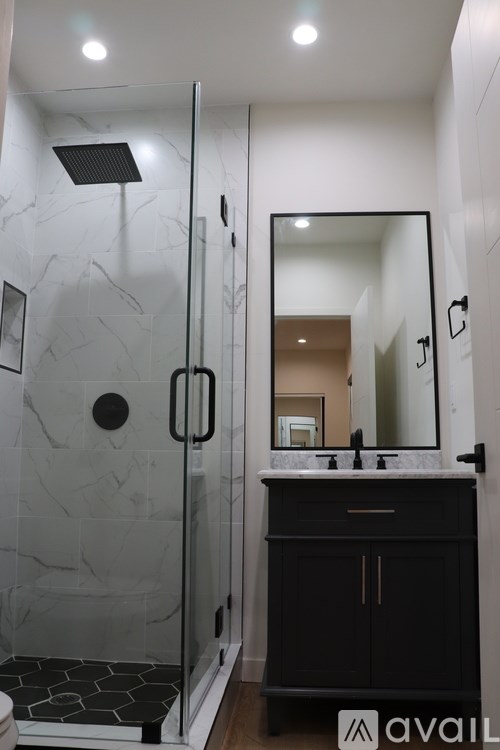 A bathroom with a marble shower and a black vanity.