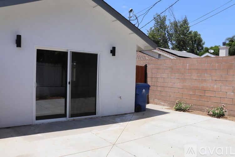 A white house with a blue trash bin outside.