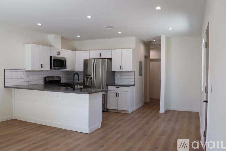 A kitchen with white cabinets and a wooden floor.
