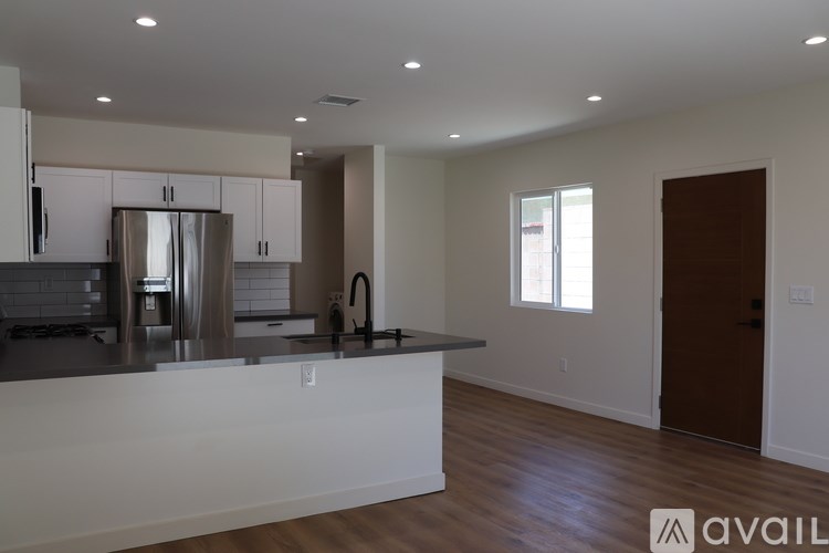 A kitchen with a refrigerator, sink, and cabinets.