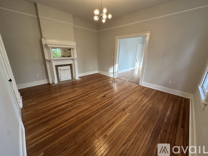 A room with wooden flooring and a fireplace.