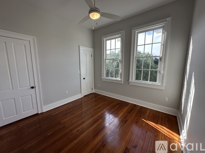 A room with a ceiling fan and two windows.