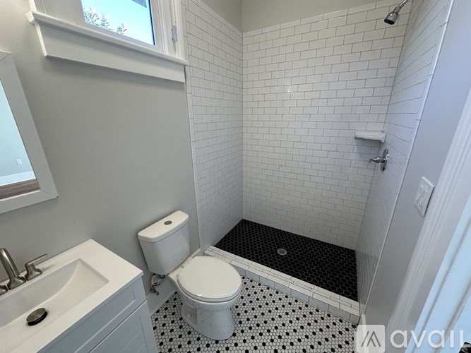 A white toilet sits in a bathroom with a black and white floor.