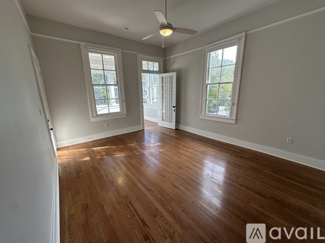 A room with wooden floors and two windows.
