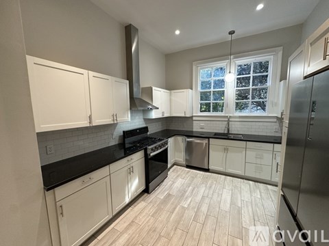 A kitchen with white cabinets and black countertops.