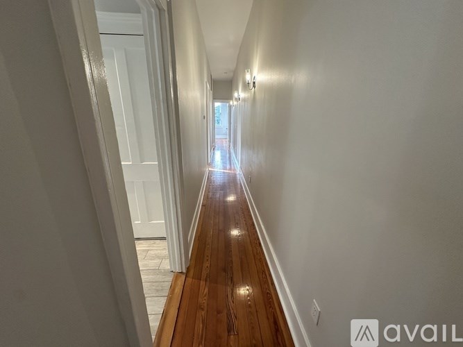 A long hallway with wooden floors and white walls.