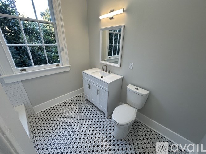A bathroom with a toilet, sink, and window.