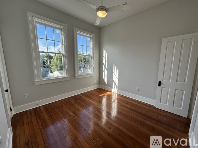 A room with wooden floors and two windows.