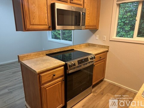 A kitchen with wooden cabinets and a black microwave above the stove.