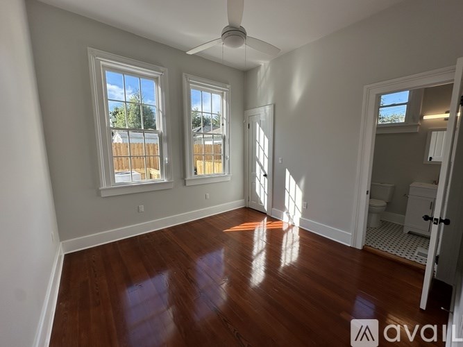A room with wooden floors and three windows.