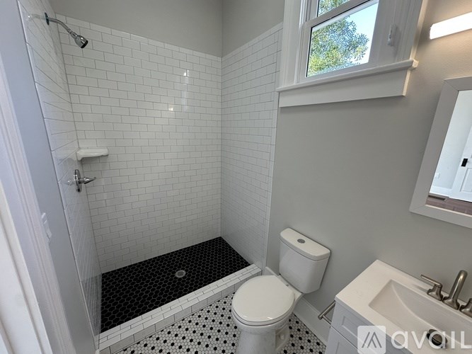 A white toilet sits in a bathroom with a black and white tile floor.