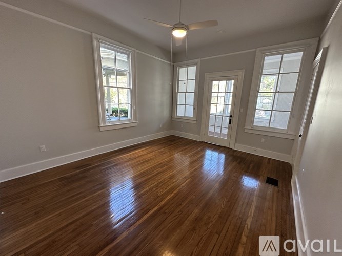A room with wooden floors and three windows.