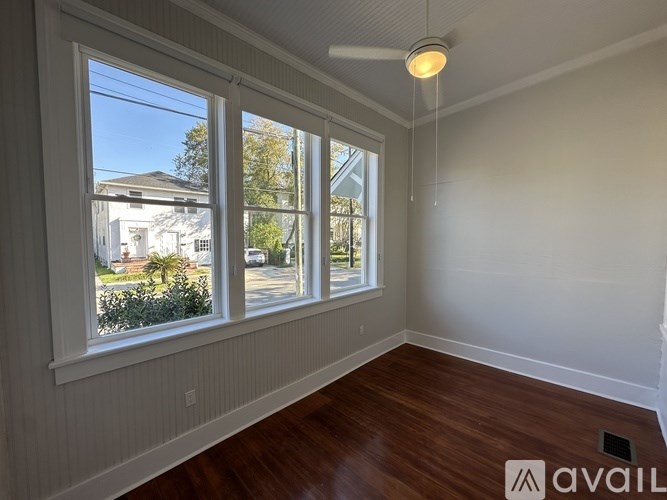A room with wooden floors and a large window overlooking a residential street.