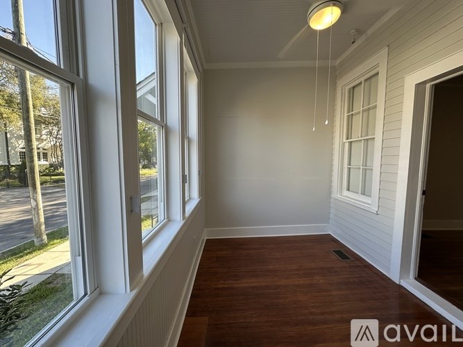 A room with wooden floors and white walls, with a window overlooking a street.