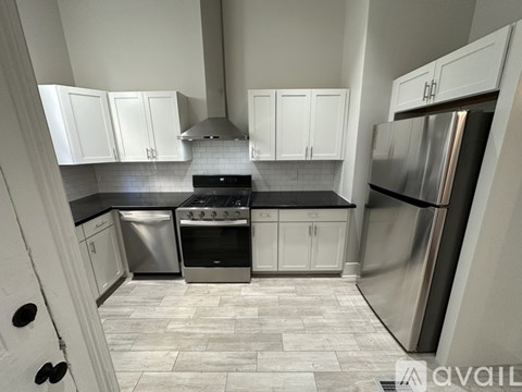 A kitchen with white cabinets and a stainless steel refrigerator.