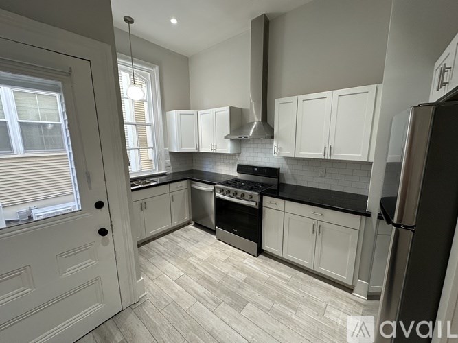 A kitchen with white cabinets and a black countertop.