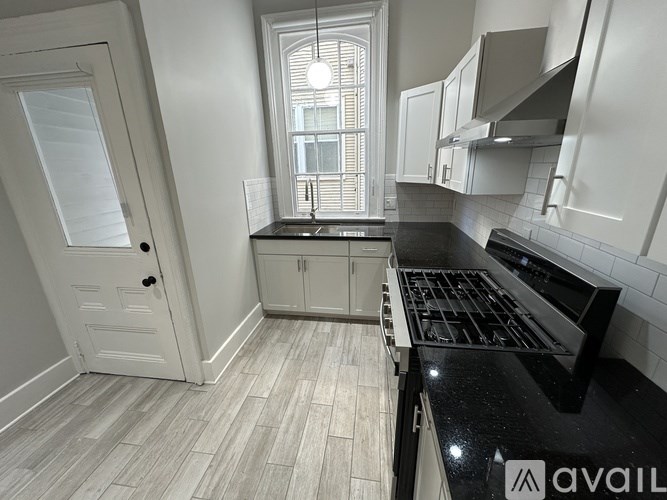 A kitchen with a black countertop and white cabinets.