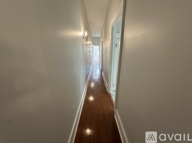 A long hallway with a wooden floor and white walls.