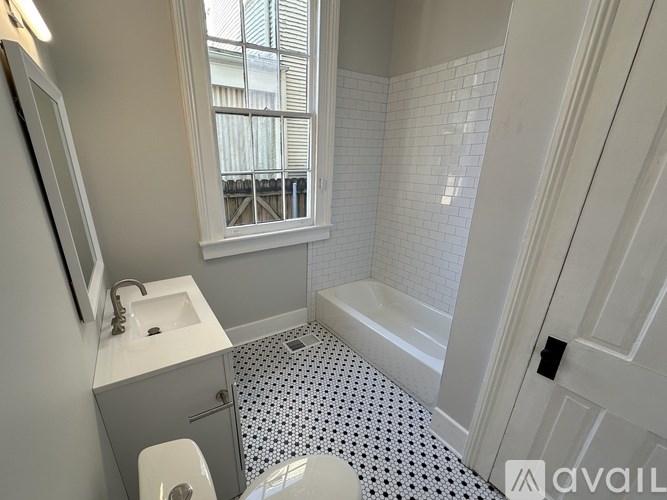 A bathroom with a white sink, toilet, and bathtub with a black and white floor.