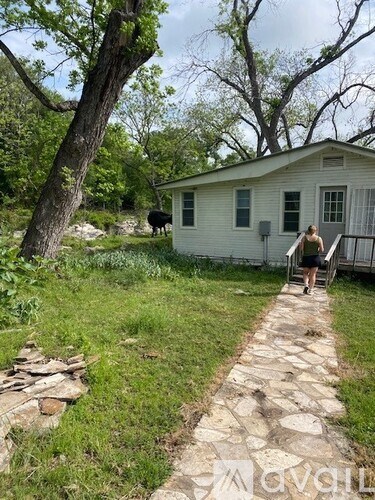 A woman is walking down a stone path towards a white house.