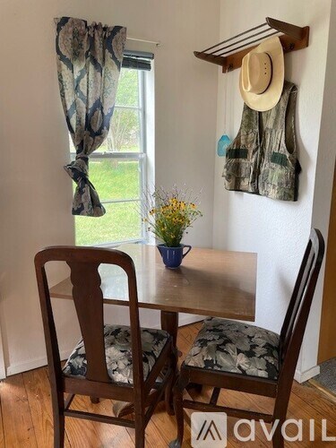 A table with two chairs and a hat hanging on the wall.