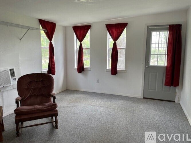 A room with a brown chair and red curtains.