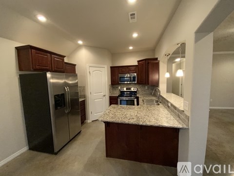 A kitchen with dark brown cabinets and a granite countertop.