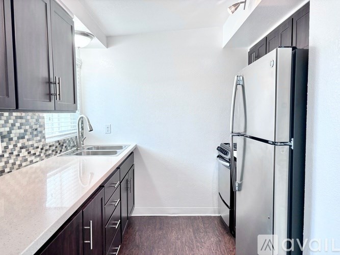 A kitchen with a refrigerator, sink, and cabinets.