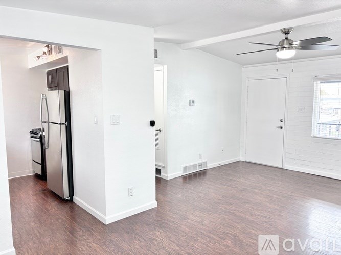A kitchen area with a refrigerator and a fan on the ceiling.