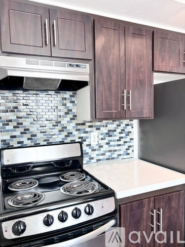 A kitchen with a black stove top oven and wooden cabinets.