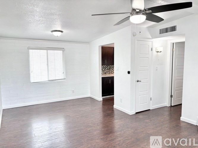 A room with a ceiling fan and wooden flooring.
