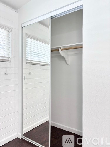 A white closet with a mirror and a shelf.